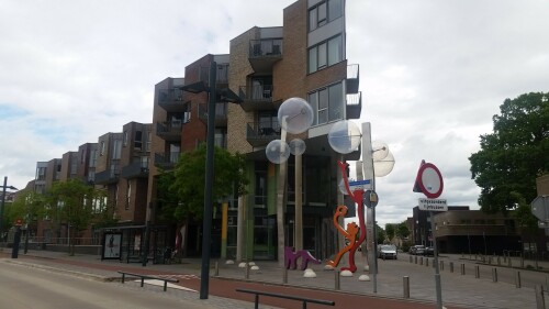 Der 13. Mai 2000 war ein schwarzer Tag in der niederländischen Stadt Enschede. Mitten im Stadtteil Roombeek explodierte die Feuerwerkfabrik S. E. Fireworks. 177 Tonnen Feuerwerkskörper legten das ganze Stadtquartier in Trümmer.

23 Menschen – darunter vier Feuerwehrmänner – starben, 947 Menschen wurden verletzt. 1.500 Wohngebäude wurden durch die Explosion beschädigt oder gerieten durch umherfliegende Feuerwerkskörper in Brand. 200 Wohnhäuser wurden vollständig zerstört und rund 300 als unbewohnbar erklärt. Darüber hinaus wurden über 100 Betriebe beschädigt. In nur einer Stunde verlieren mehr als 1.250 Einwohner ihr Zuhause.

Etwa zwei Drittel des 65 Hektar großen Stadtviertels, welches nördlich an den Hauptbahnhof und die Innenstadt anschließt, waren durch die Explosion betroffen. Mit der Katastrophe waren jedoch auch Chancen und Entwicklungspotenziale verbunden, welche einen Neuanfang für das durch die sterbende Textilindustrie geprägte Quartier bedeuten.

Der für den Wiederaufbau entwickelte Masterplan von Pi de Bruijn (de Architecten Cie. aus Amsterdam - www.cie.nl/projects/53 | Video: https://vimeo.com/51809482) verkörpert eine State of the Art-Stadtplanung. Die 1350 neu errichteten Wohnungen befinden sich in einem durchmischten Gebiet, welches durch kulturelle Angebote, Geschäfte und soziale Einrichtungen ergänzt wird. Freiräume, Wasser und Grün spielen ebenfalls eine große Rolle.

Dabei hat Pi de Bruijn den Einwohnern große Freiheit gelassen, selbst zu bestimmen, wie ihre Nachbarschaft aussehen soll. Üblicherweise macht die niederländische Stadtplanung vergleichsweise viele Vorgaben und lässt wenige Freiheiten. In Roombeek konnten rund 50 Prozent der Einwohner ihre neuen Wohngebäude vollkommen frei entwerfen, nur für die Bereiche an den Hauptverkehrsachsen wurden strengere Vorgaben gemacht. Das Straßennetz wurde exakt in der Form wieder aufgebaut, in der es vor der Explosion existierte. Dies sollte den ehemaligen Bewohnern ein rasches Ankommen und Einleben ermöglichen. Zudem wurde versucht, die vereinzelten noch stehenden Gebäude, soweit es geht, zu sichern und weiterzuentwickeln.