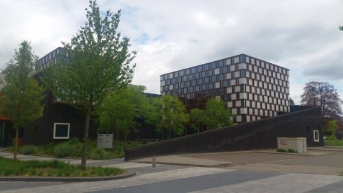 Der 13. Mai 2000 war ein schwarzer Tag in der niederländischen Stadt Enschede. Mitten im Stadtteil Roombeek explodierte die Feuerwerkfabrik S. E. Fireworks. 177 Tonnen Feuerwerkskörper legten das ganze Stadtquartier in Trümmer.

23 Menschen – darunter vier Feuerwehrmänner – starben, 947 Menschen wurden verletzt. 1.500 Wohngebäude wurden durch die Explosion beschädigt oder gerieten durch umherfliegende Feuerwerkskörper in Brand. 200 Wohnhäuser wurden vollständig zerstört und rund 300 als unbewohnbar erklärt. Darüber hinaus wurden über 100 Betriebe beschädigt. In nur einer Stunde verlieren mehr als 1.250 Einwohner ihr Zuhause.

Etwa zwei Drittel des 65 Hektar großen Stadtviertels, welches nördlich an den Hauptbahnhof und die Innenstadt anschließt, waren durch die Explosion betroffen. Mit der Katastrophe waren jedoch auch Chancen und Entwicklungspotenziale verbunden, welche einen Neuanfang für das durch die sterbende Textilindustrie geprägte Quartier bedeuten.

Der für den Wiederaufbau entwickelte Masterplan von Pi de Bruijn (de Architecten Cie. aus Amsterdam - www.cie.nl/projects/53 | Video: https://vimeo.com/51809482) verkörpert eine State of the Art-Stadtplanung. Die 1350 neu errichteten Wohnungen befinden sich in einem durchmischten Gebiet, welches durch kulturelle Angebote, Geschäfte und soziale Einrichtungen ergänzt wird. Freiräume, Wasser und Grün spielen ebenfalls eine große Rolle.

Dabei hat Pi de Bruijn den Einwohnern große Freiheit gelassen, selbst zu bestimmen, wie ihre Nachbarschaft aussehen soll. Üblicherweise macht die niederländische Stadtplanung vergleichsweise viele Vorgaben und lässt wenige Freiheiten. In Roombeek konnten rund 50 Prozent der Einwohner ihre neuen Wohngebäude vollkommen frei entwerfen, nur für die Bereiche an den Hauptverkehrsachsen wurden strengere Vorgaben gemacht. Das Straßennetz wurde exakt in der Form wieder aufgebaut, in der es vor der Explosion existierte. Dies sollte den ehemaligen Bewohnern ein rasches Ankommen und Einleben ermöglichen. Zudem wurde versucht, die vereinzelten noch stehenden Gebäude, soweit es geht, zu sichern und weiterzuentwickeln.