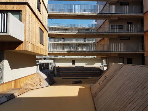 Die Gestaltung des Bauplatzes D12 in Wien Aspern steht ganz im Zeichen des Baustoffes Holz. Die aktive Zone der Wohnsiedlung ist der Begegnungsraum und Jugendspielplatz – der Canyon. Ein einheitlicher EPDM Belag trägt zum Schallschutz bei. In ihm liegen frei verteilt Holzobjekte und -flächen. Die Holzverkleidung entlang der Rampenwände wächst stellenweise aus der Wand und bildet eine schräge Fläche zum Anlehnen bzw. als Kletterwand. Große vertikale Flächen verbinden sich mit der Wand und bilden Liege- oder Nutzflächen.

Bauherrschaft: EBG Gemeinnützige Baugen. reg. m.b.H.

Architektur :querkraft architekten, Berger + Parkkinen Architekten

Die Seestadt Aspern ist eines der größten Stadtentwicklungsprojekte Europas der 2010er Jahre. Über einen Zeitraum von rund 20 Jahren soll ein neuer Stadtteil entstehen, in dem über 20.000 Menschen wohnen und arbeiten sollen. Die erste von drei Entwicklungsetappen konzentriert sich auf den Süden des Stadtteils und soll 2020 abgeschlossen sein.