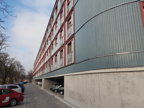 Um den Wohnungsmangel in München zu dämpfen, wurde der weiterhin genutzte öffentliche Parkplatz am Dantebad mit einem Wohngebäude überbaut.

Im Rahmen des Wohnungsbausofortprogramms der Landeshauptstadt München realisierte die städtische Wohnungsbaugesellschaft GEWOFAG das Pilotprojekt im Stadtteil Moosach am Wintereingang des Dantebads entlang der Homerstraße. Auf dem knapp 4.200 m2 großen Grundstück, das sich im Eigentum der Stadt befindet, wurden über dem öffentlichen Parkplatz 100 neue Wohnungen errichtet, davon 86 Einzimmerwohnungen (24 bis 31 Quadratmeter) und 14 Wohnungen mit 2,5 Zimmern (48,8 bis 54 Quadratmeter). Der Quadratmeterpreis liegt bei 9,40 Euro (kalt).

Der Großteil der Parkplätze konnte trotz der Überbauung erhalten werden. Das Grundstück ist gut an öffentliche Verkehrsmittel angebunden.

Der neue Wohnkomplex steht auf einer Betonrahmenkonstruktion mit Stahlbetondecke. Die darüberliegenden vier Stockwerke sind in Holzsystembauweise gefertigt. Die Bauzeit betrug 180 Tage. Inklusive Planung, Ausschreibung, Baugenehmigung sowie Bauphase hat das Projekt etwa ein Jahr gedauert.

Das schwellenfreie Gebäude besitzt insgesamt fünf Geschosse inklusive der Parkplätze, die nach der Fertigstellung zum Großteil wieder genutzt werden können. Es gibt Treppen sowie einen Aufzug. Vier Wohnungen sind rollstuhlgerecht. Bei Bedarf können weitere Wohnungen so umgerüstet werden. Gemeinschaftsräume, Aufweitungen von Laubengängen und Freiflächen auf dem Dach bieten den Mieterinnen und Mietern Möglichkeiten des Aufenthalts außerhalb ihrer Wohnung und zur Begegnung.

Film: https://www.youtube.com/watch?v=TrHFjZ_Zhd8